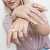 Blonde girl showing her two hands with armcandymtl rings on all her fingers.